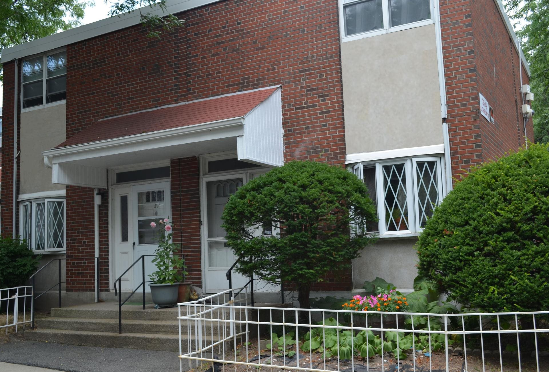 A red brick house with a white fence in front.
